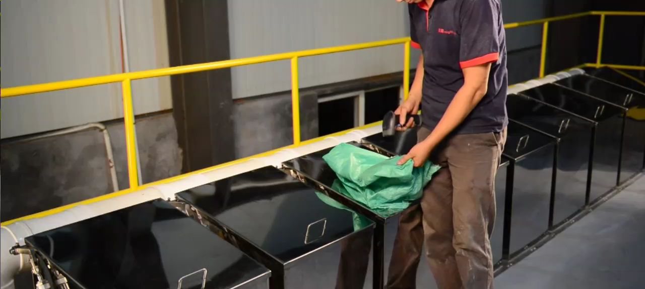 Operator scanning a material sack barcode before it enters the weighing hopper