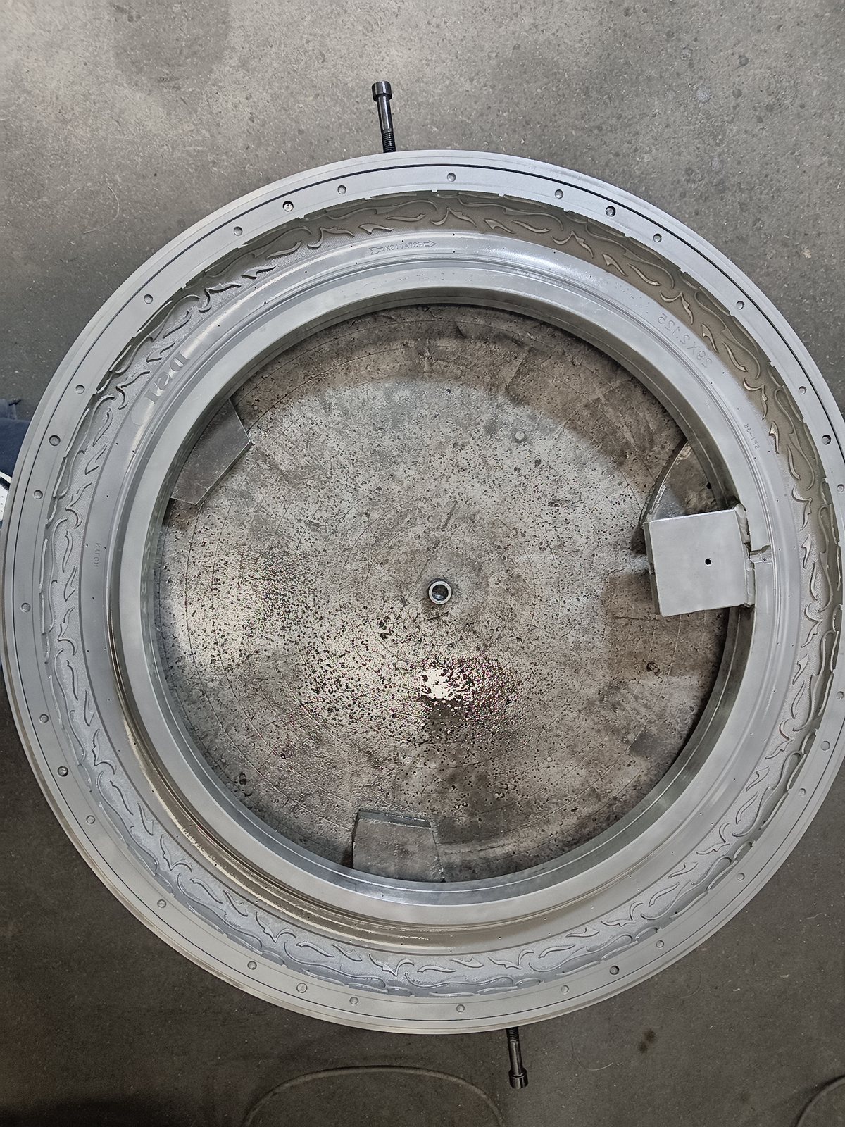 Bottom half of a bicycle tire mold, showing engraved sidewall pattern and curing cavity