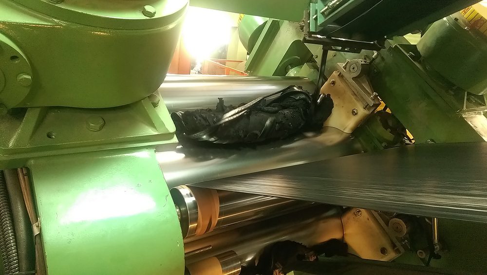 Close-up of nylon cord fabric passing through the rubberizing calender rolls