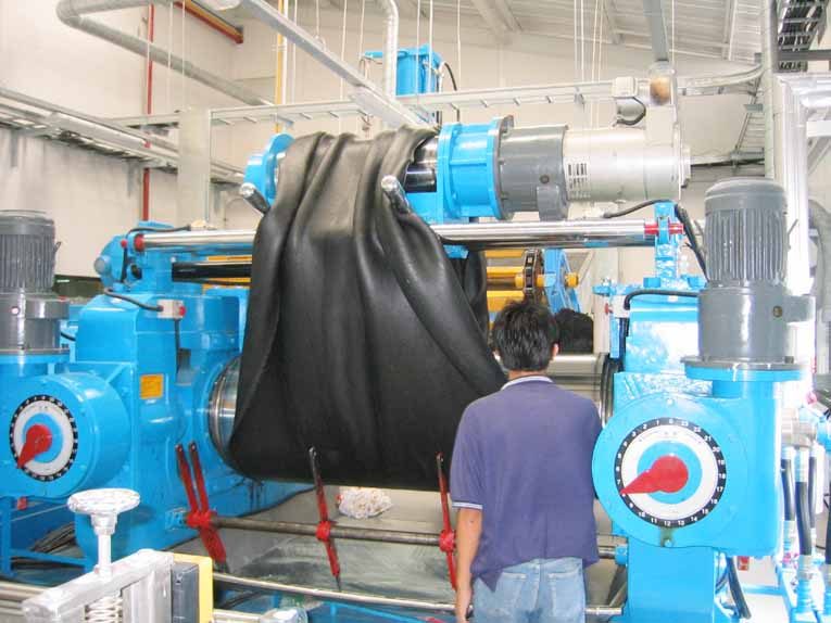 Open mixing mill working a batch of black compound